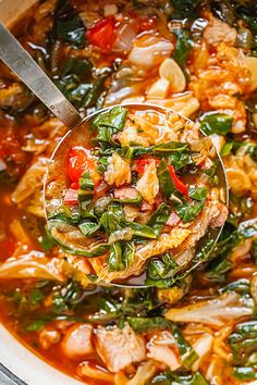 a spoon full of soup with meat, vegetables and spinach in it is being held by a ladle