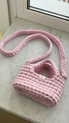 a pink handbag sitting on top of a counter next to a window sill