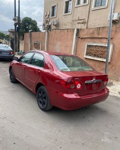 a red car is parked on the side of the road in front of a building