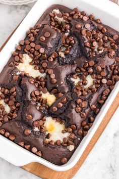 a chocolate cake in a white dish on a wooden board