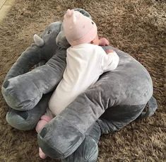 a baby laying on top of an elephant pillow