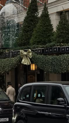 a black car parked in front of a building with christmas decorations on it's windows