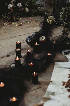 many candles are lit on the ground outside