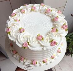 a white cake with pink and green flowers on the top is being held up by someone's hand