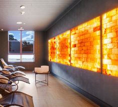 an empty waiting room with leather chairs and large art work on the wall behind it