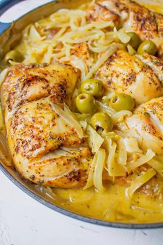 chicken with olives and pasta in a skillet on a white counter top, ready to be eaten