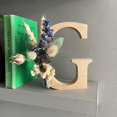 a book and some flowers sit on a shelf in front of a letter g sign