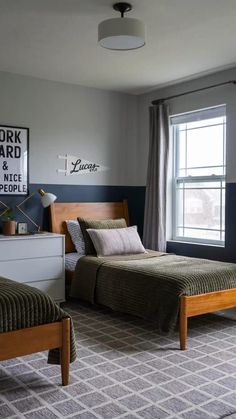 two beds in a room with blue walls and carpeted flooring next to windows