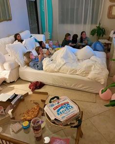 a group of people laying on top of a bed in a living room next to each other