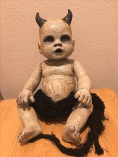 a creepy looking doll sitting on top of a wooden table