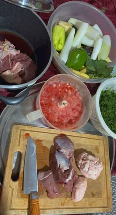 meat and vegetables are in bowls on a table next to a cutting board with knifes