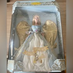 an angel doll in a box with gold wings