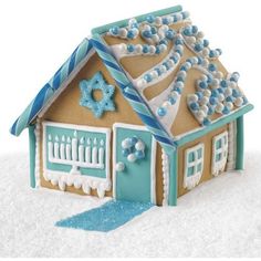 a gingerbread house is decorated with blue and white icing, snowflakes and decorations