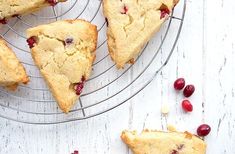 several pieces of cherry scones on a wire rack next to some cranberries