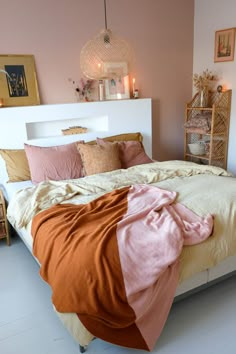 a bed with blankets and pillows on top of it next to a shelf filled with candles