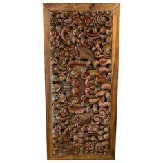 an intricately carved wooden wall panel with shells and leaves on the bottom, against a white background