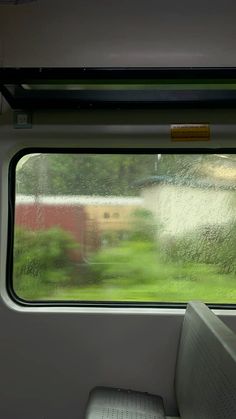 the inside of a train car with rain on it's windows and grass outside