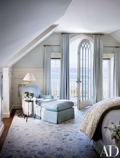 a bedroom with an arched window, bed and chair in it's center area