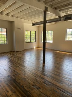 an empty room with hard wood floors and exposed beams in the ceiling, windows on both sides