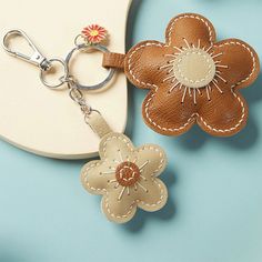 two leather flower keychains on a blue background