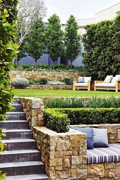 an outdoor seating area with stone walls and steps leading up to the grass covered lawn