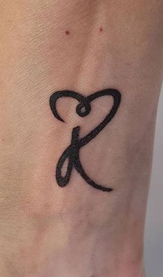 a small tattoo on the foot of a woman's lower leg, with an initial letter