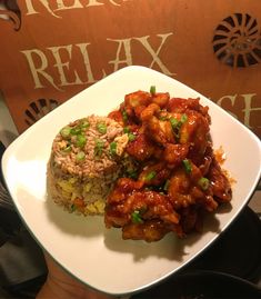 a white plate topped with rice covered in sauce and chicken next to a brown sign