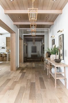 an empty hallway with wooden floors and chandelier hanging from the ceiling above it