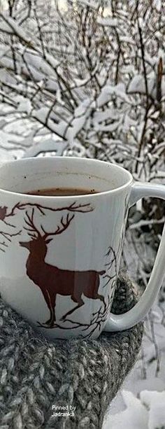 a cup of coffee sitting on top of a table covered in snow