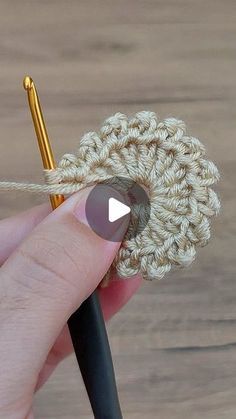 the crochet flower is being worked on by someone using a knitting needle to make it