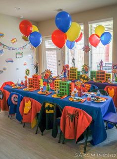 a room filled with lots of tables covered in blue and red table cloths, balloons and decorations