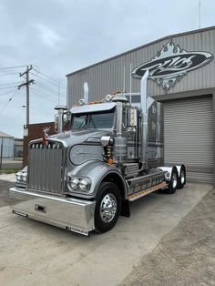 a silver semi truck parked in front of a building