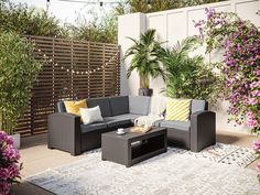 an outdoor living area with couches, tables and potted plants