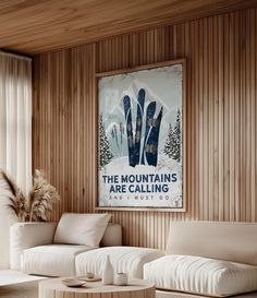 a living room filled with furniture and a poster on the wall above it that says the mountains are calling