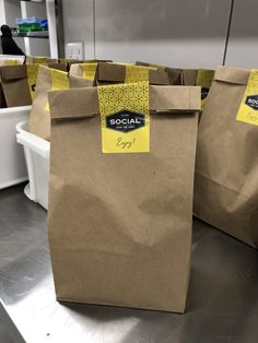 brown paper bags with yellow stickers on them are lined up in a row and ready to be sold