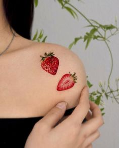 a woman's shoulder with two strawberries on it