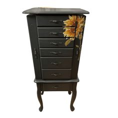 a black cabinet with sunflowers painted on the front and bottom drawers, sitting against a white background