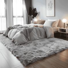 a bedroom with white walls and wooden flooring is pictured in this image, there are two lamps on either side of the bed