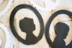 the silhouettes of two women are next to each other on a wooden table with white and black scalloped paper