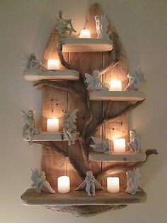 a wooden shelf with candles on it and angels in the tree around it that is hanging from the wall