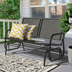 a metal bench sitting on top of a porch next to a potted green plant