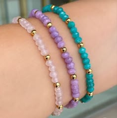 three bracelets with different colored beads and gold balls on the wrist, one is for women