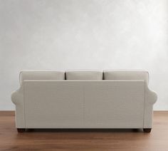 a couch sitting on top of a wooden floor next to a white wall and wood floors