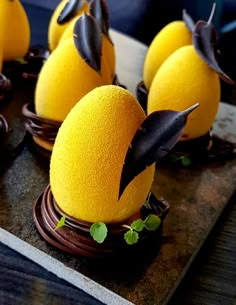 there are some yellow desserts with black decorations on top of each one in the shape of bats