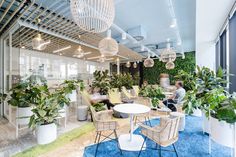 an office filled with lots of plants and people sitting at tables in front of them