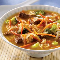 a bowl of soup with broccoli, carrots and rice