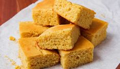 several pieces of cornbread sitting on top of a piece of wax paper next to a wooden table