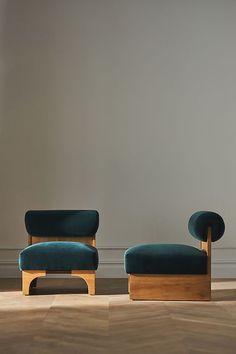 two chairs sitting next to each other on top of a hard wood floor in front of a gray wall