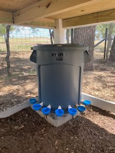 a blue trash can sitting under a wooden structure