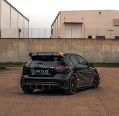 a black sports car parked in a parking lot next to a building with two garage doors